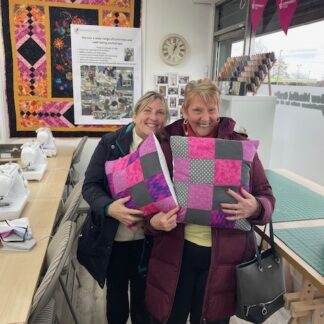 Two women showing their handmade cushions