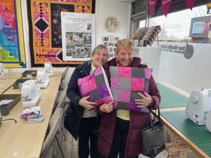 Two women showing their handmade cushions