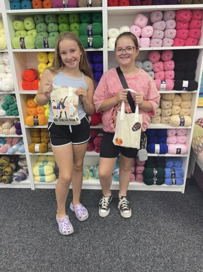 Two girls showing their handmade bags
