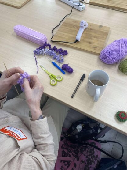 A lady crocheting flowers with yarn
