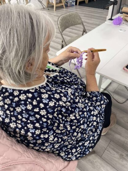 A lady crocheting with purple yarn
