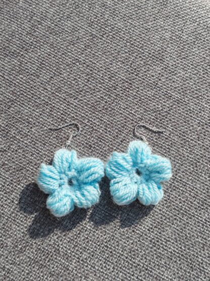 A pair of blue crocheted flower earrings, attached to ear wires.