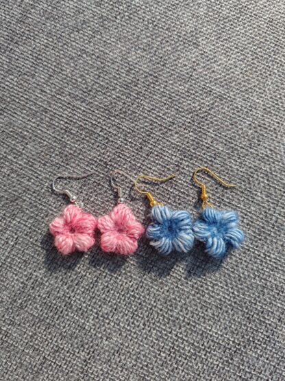 A pair of blue and pink crocheted flower earrings, attached to ear wires.