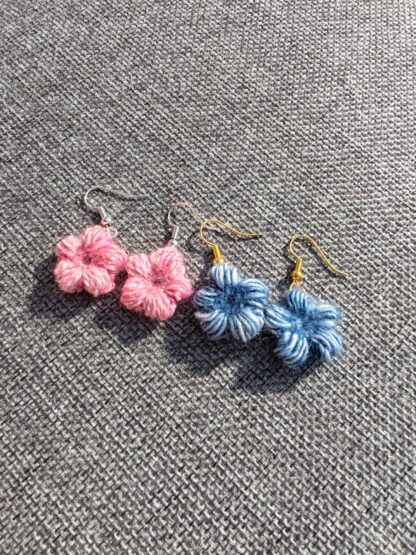 A pair of blue and pink crocheted flower earrings, attached to ear wires.
