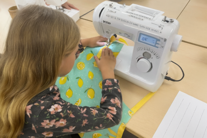 Child using a sewing machine to make an apron