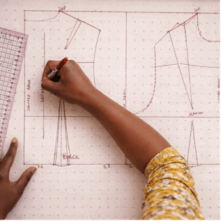 person drawing on draft paper for fashion design